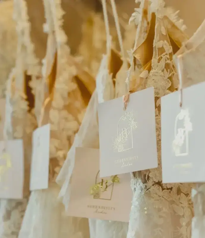 A close-up image of hanging wedding dresses with tags displaying the name of a bridal store or designer.